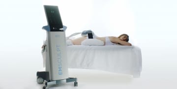 woman laying down on stomach with emsculpt body sculpting device on buttocks