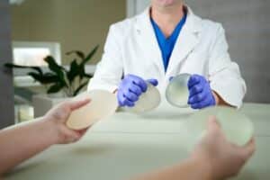 A cropped photo of a woman in a white bra after breast augmentation surgery